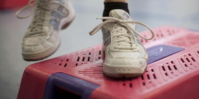 Nahaufnahme eines Sportschuhs auf einem pinken Stepper im Fitnessstudio.